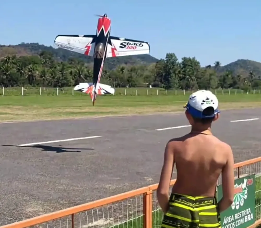 Breno Vilarim criança no campo, com o aeromodelo Sbach 300 em voo